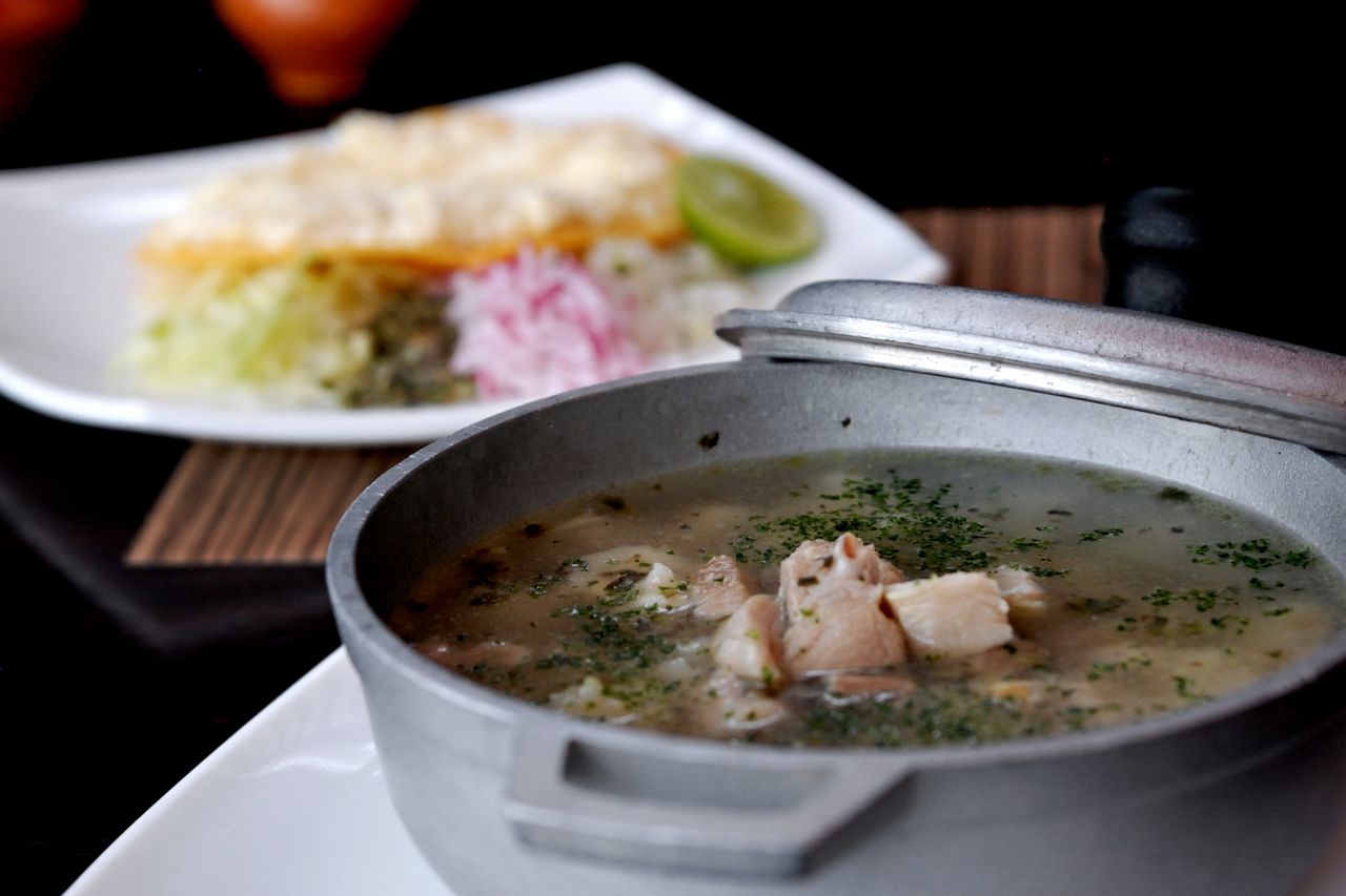 Delicious Mexcian soup served in a traditional pot, paired with sides.