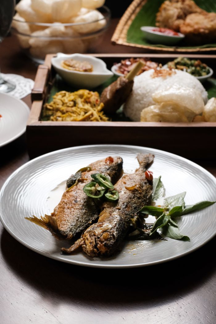 Delicious fried fish served with rice and traditional condiments on a rustic table setting.