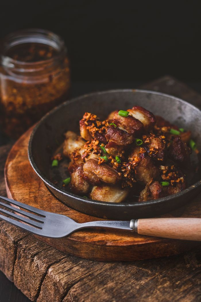 Delicious Filipino pork sisig garnished with crispy garlic and chives in a rustic setting.